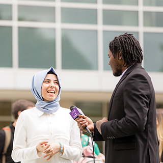 Bob Schieffer College of Communications A student reporter holds a microphone up to a student wearing a hijab while a student with a video camera records the interview