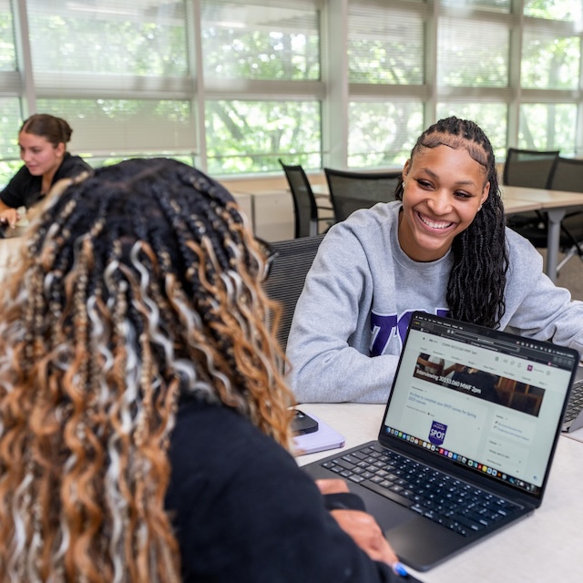 Two students sitting a table with a laptop open