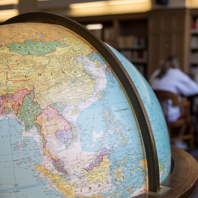 A globe in the foreground with students studying in the background