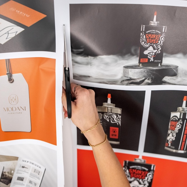 A hand using scissors cuts through paper design project