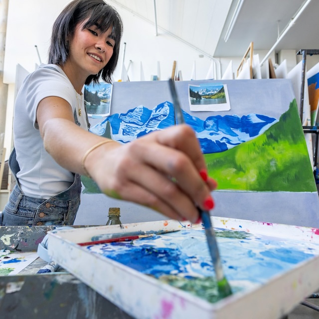 Student dips paintbrush in paint