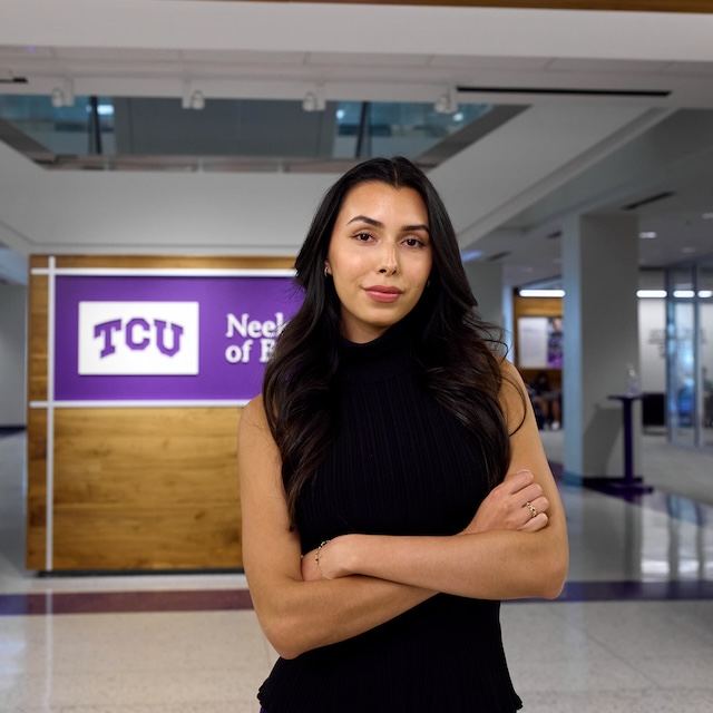 Student stands in front of Neeley School of Business sign inside
