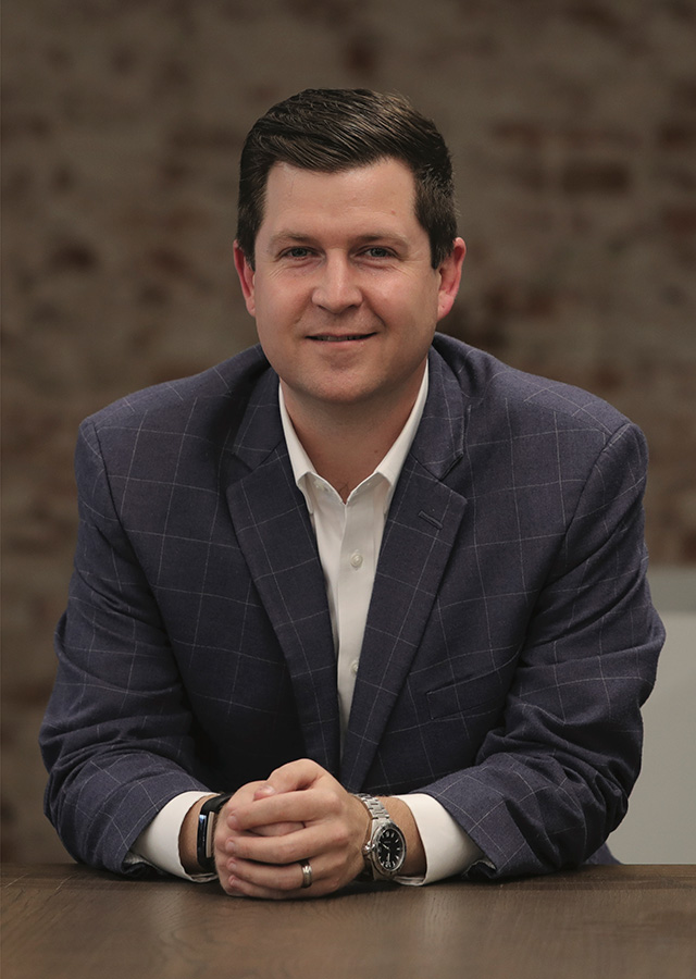 Jeremy Vickers, seated at a conference table in a business suit