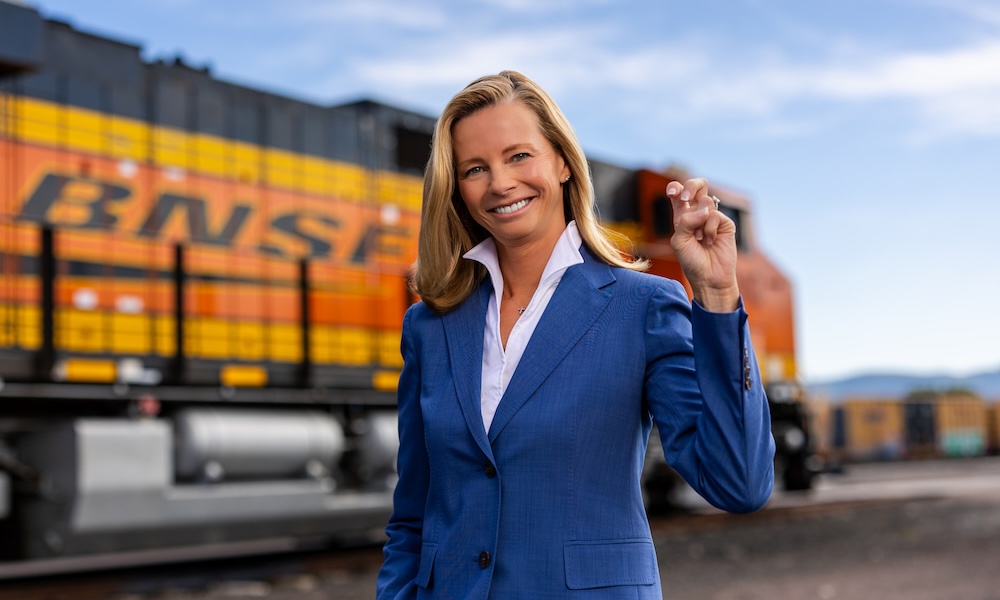 Katie Farmer holds up "Go Frogs" hand sign with a BNSF train in the background