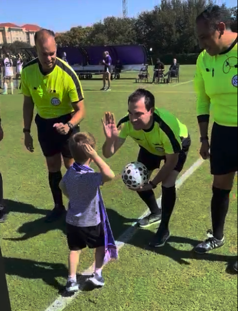 young child gives a high five to referees